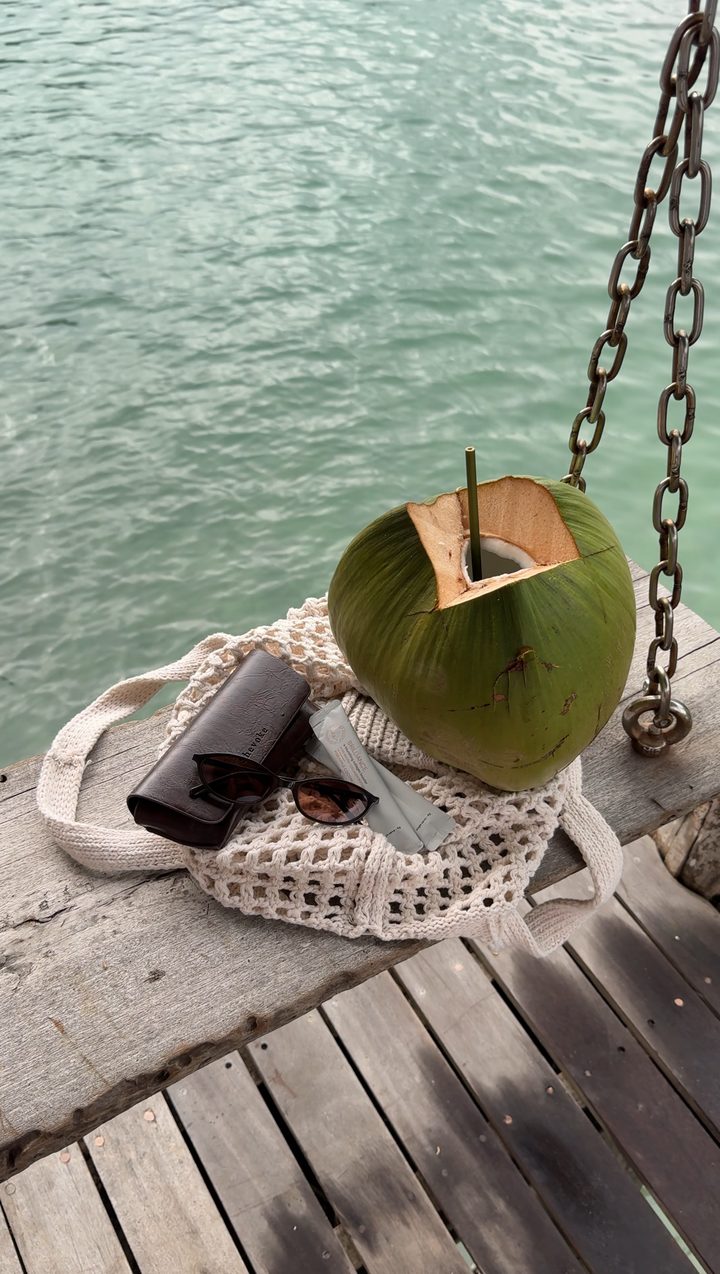 Fresh coconut and a woven bag on a dock