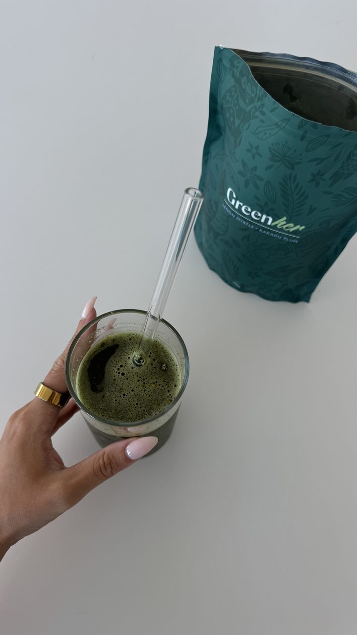 Green drink in a glass beside its pouch